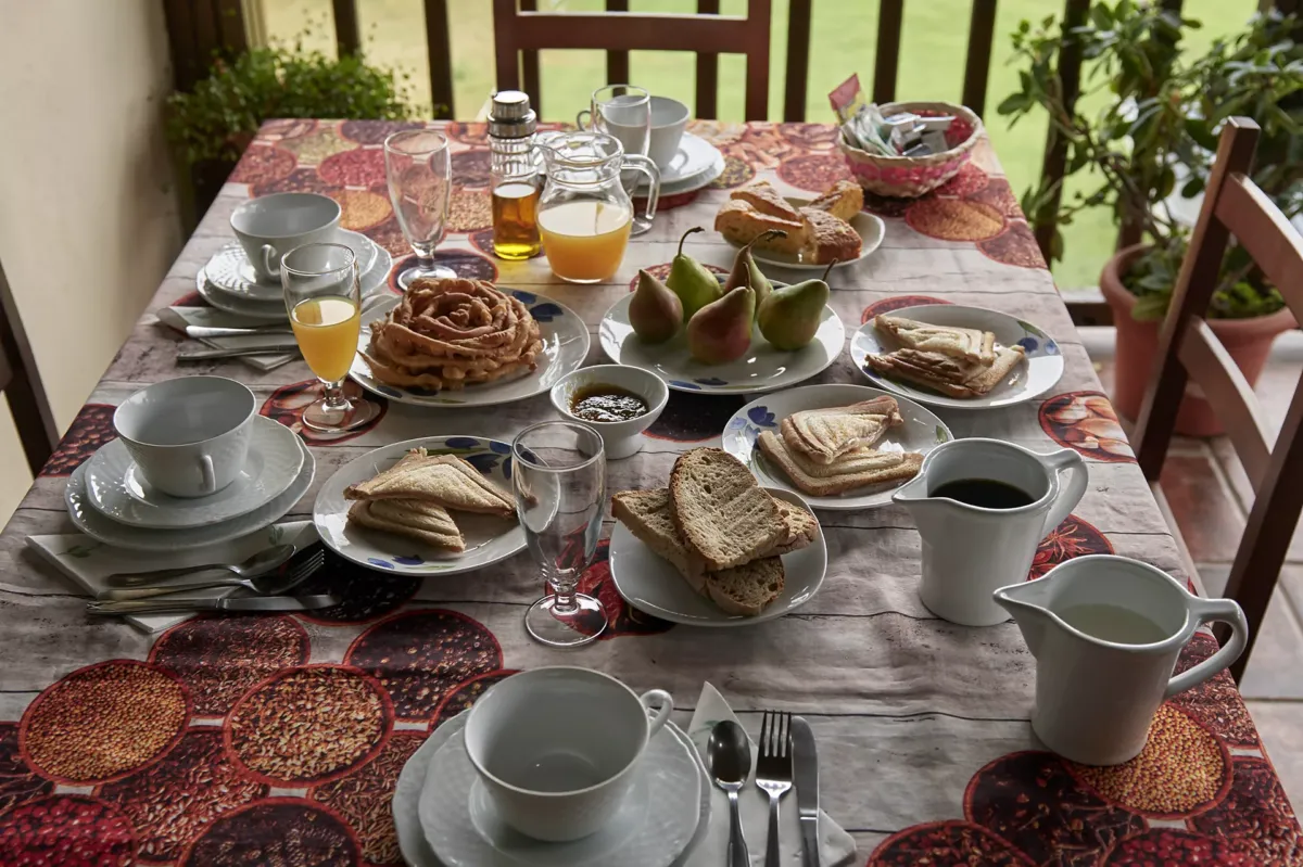 Mesa con desayuno en la terraza: cafés, pan, sándwiches,peras, zumos, mermeladas, bizcocho....